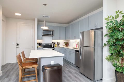 Compact kitchen fully stocked with all essentials and sleek stainless steel appliances—everything you need in a cozy space.