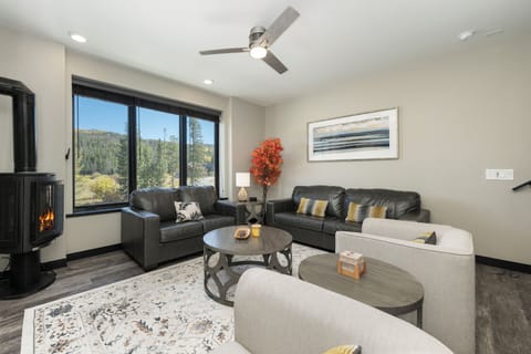 Unwind in your inviting living space with plush leather seating, cozy fireplace, and stunning mountain views through expansive windows.