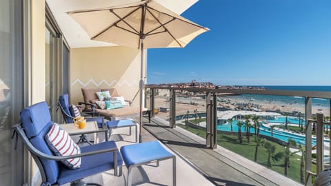 The balcony calls too your with its double chaise lounge chair, and two chairs with ottomans under a sun umbrella