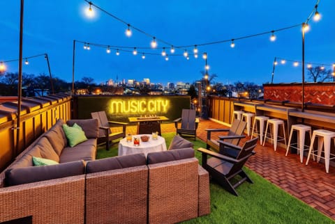 Bar seating on the rooftop deck with a Music City neon sign and downtown views is where pre-game rounds happen before you hit the honky-tonks
