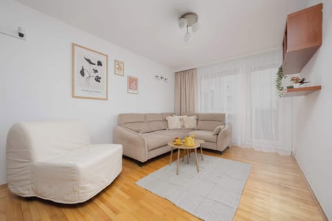 A bright living room with a comfortable corner sofa and armchairs creates a perfect space for relaxing evenings, with a large window letting in plenty of natural light.