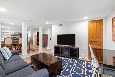 A bright open-concept living area with a comfy sofa, smart TV, and plenty of space to relax after a day exploring New Orleans.