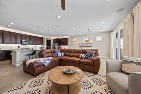 Relax with family and friends in this open-concept space, featuring a comfy leather sectional, plenty of natural light, and an easy flow into the fully stocked kitchen.