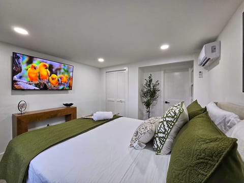 Cozy and modern bedroom featuring a Queen-size bed, lush green bedding, and a large Smart TV for your entertainment. Includes air conditioning and a tranquil ambiance for a perfect night`s sleep.