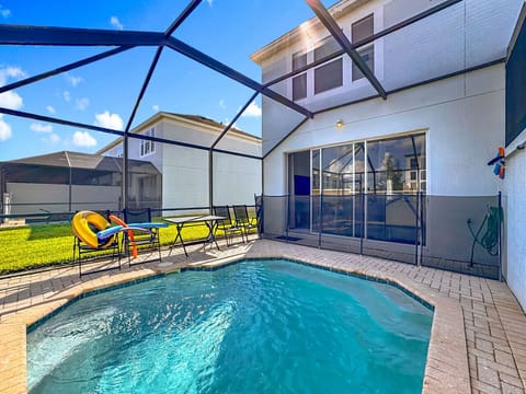 Bright and open backyard pool with chairs and loungers for relaxation.