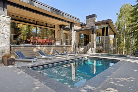 Contemporary mountain home exterior with pool, terrace, and tall pine trees