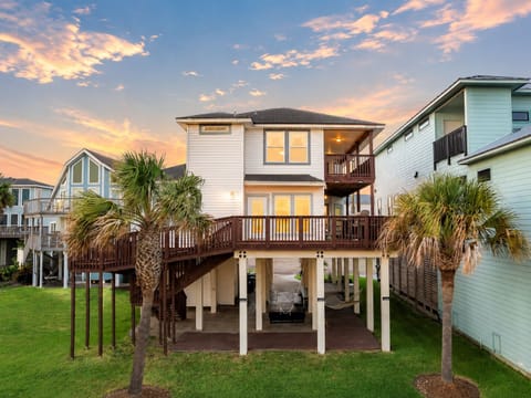 Beachfront Galveston vacation home with elevated decks, palm trees, coastal exterior, and spacious outdoor areas near the Gulf shoreline.