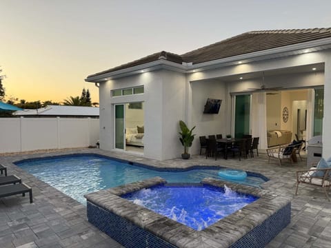 Resort-style backyard oasis featuring a sparkling pool, glowing spa, and modern coastal design