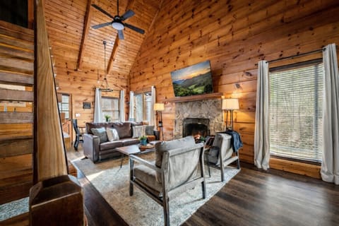 Walk into a bright, open living space where high ceilings, warm wood, and a glowing fireplace welcome you to settle in and make yourself at home.
