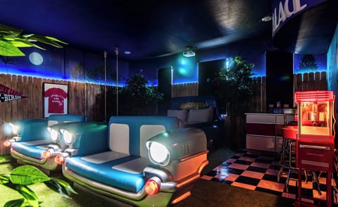 50s drive-in room with pickup truck bed, car-seat sofas & movie projector