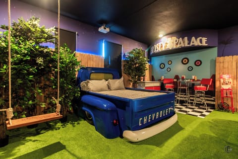 50s drive-in room with pickup truck bed, car-seat sofas & movie projector