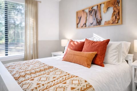 Sun-washed bedroom offering a comfortable queen bed and an overhead fan. 