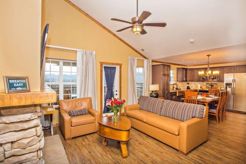 Open-concept living area with sofa seating, fireplace, and TV in a cozy mountain style.