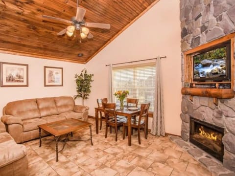 Living room with sofa, fireplace, and dining table under a vaulted wood ceiling.
