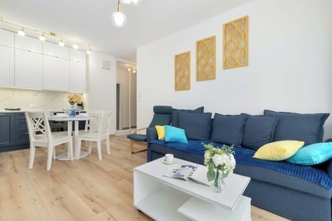 Elegant living room featuring a navy-blue sofa, matching armchair, and a bright dining space with modern wall art.