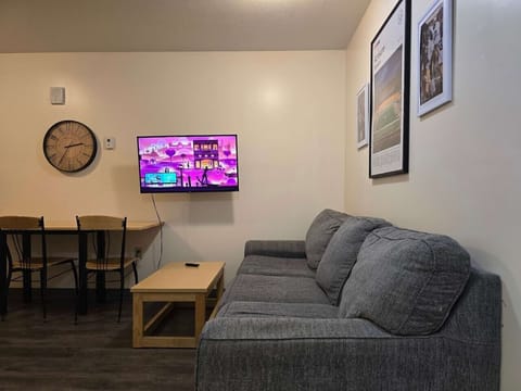 Cozy living area w/ plush sofa & wall clock, TV set up for movie nights.