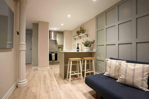 A warm, contemporary living area with soft lighting, sleek wood floors, and a statement blue couch. Comfort and elegance blend seamlessly for a space that feels both stylish and welcoming.