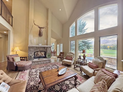 The great room with ample seating, a warm fireplace and a view of the valley and golf course