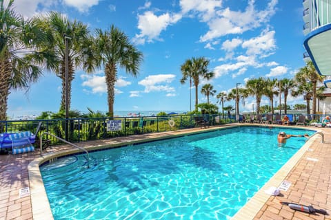 Outdoor pool with sparkling water and lush palms, perfect for a serene retreat.