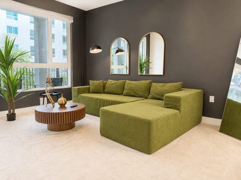 Spacious living room featuring a cozy L-shaped sofa, a full-size air mattress, and a 65" Smart TV with preloaded access to Netflix, Hulu, and Disney+, all set up for your enjoyment.