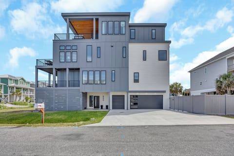 Modern coastal home featuring contemporary architecture with multiple levels, balconies, and spacious garage in a residential neighborhood.