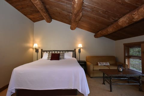 Cozy bedroom under rustic wooden beams, offering a warm and inviting retreat.