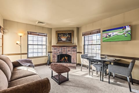 A cozy living room with one sofa, TV, gas burning fireplace, and dining table for two guests.