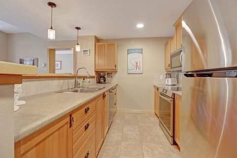 Bright and functional full kitchen featuring warm wood cabinetry, stainless steel appliances, and generous counter space—perfect for preparing meals before or after mountain adventures.