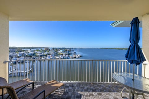 View from the private top-floor balcony overlooking Boca Ciega Bay and the marina, with water glistening in the sun and boats gently docked