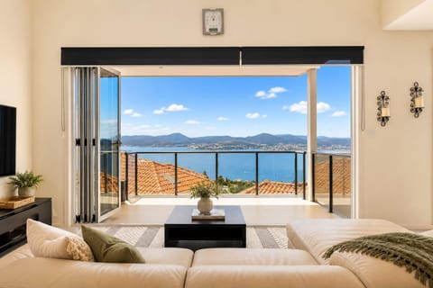 Living room looking through to balcony — Indoor-outdoor living at its best, with the lounge opening directly onto the balcony and panoramic water views beyond.
