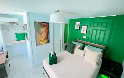 Bright and inviting bedroom in The Green Room, featuring a queen bed, fresh green accents, and a clean, modern design.
