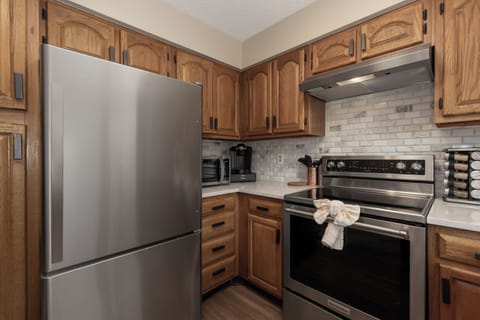 Your fully equipped kitchen invites culinary adventures with warm wood cabinets, stainless appliances, and elegant subway tile backsplash.