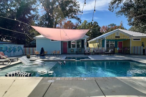 Luxe Chalets! resort-style pool area with a central swimming pool, shaded lounge seating, string lights overhead, and colorful cottages creating a relaxed, social atmosphere.