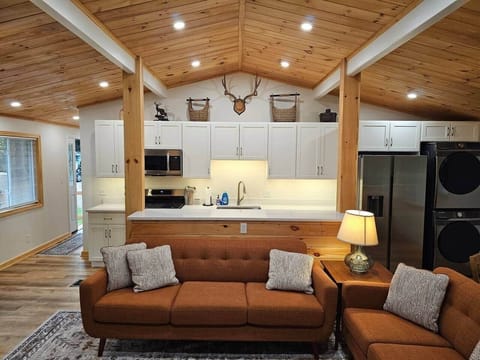 Step into a bright, modern-rustic space with a tongue-and-groove ceiling, warm beams, and dimmable lighting. Enjoy quartz counters, white cabinetry, stainless appliances, and mid-century sofas in the open living area.