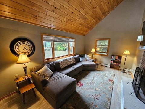 Relax in this inviting living room with soaring wood ceilings, oversized windows, and a plush sectional. Gather by the fireplace, enjoy the 65” TV, or unwind with board games on the cozy rug—perfect for families after a day in the White Mountains.
