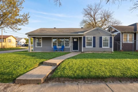 Charming Retreat: Bright exterior with inviting blue chairs and a backdrop of vibrant sunset skies!