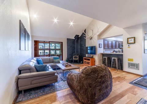Bright open living room w/ TV & wood burning fireplace.