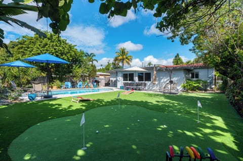 Putting green and lawn, with the pool and house beyond.