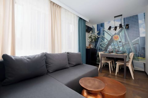 The spacious living area with a comfortable sofa and large windows invites you to relax in the flow of natural daylight.