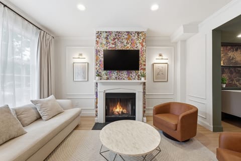 Elegant sitting room with designer floral accent wall, cozy decorative fireplace, and comfortable lounge seating — the perfect place to unwind after exploring Capitol Hill. (Fireplace is decorative only)