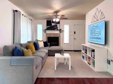 Living room with large cozy couch, 65" 4K smart TV, and games for your enjoyment. (Please do not use the fireplace. We are in the process of replacing it.)