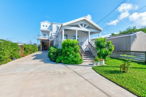Charming coastal home with covered porch and landscaped grounds, featuring convenient parking and peaceful residential setting.