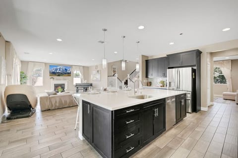 Modern open kitchen flows into the living room, featuring island seating and stainless-steel appliances.