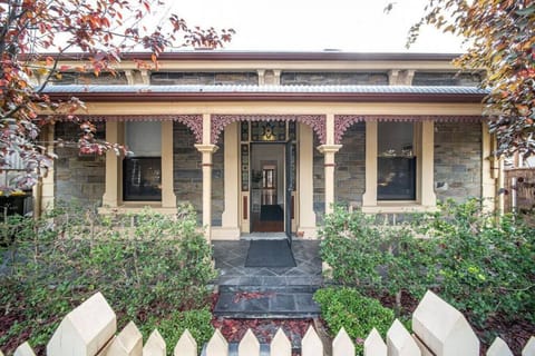 Step into a charming historic façade framed by greenery and classic verandah details.