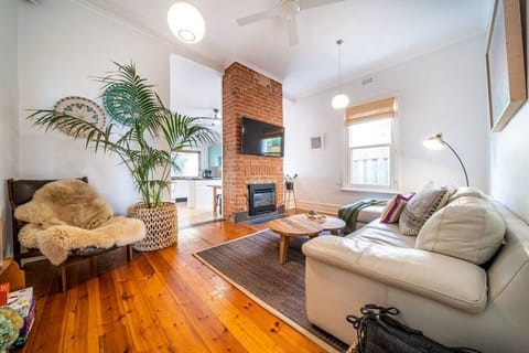 Unwind beside the exposed brick fireplace where a leather sofa and warm textures create a cosy space to relax after sunset walks along Henley Beach.