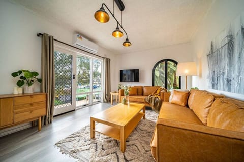 Sunlight pours through the arched doors, framing a stylish lounge setup with curated decor.