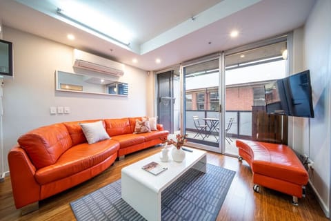 Stretch out on the vibrant sofa as natural light filters through the glass doors, creating an inviting space to unwind or enjoy a relaxed evening in.