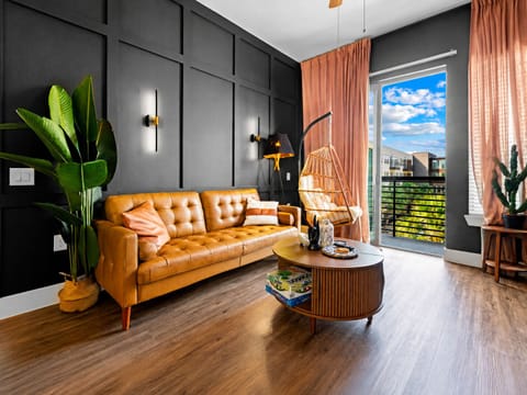 Chic living room with leather sofa, hanging chair, and sunny balcony views