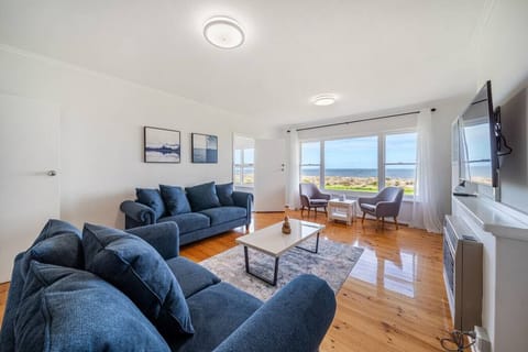 Unwind in the light-filled living room where large windows frame uninterrupted ocean views as you relax after a day on Tennyson Beach.