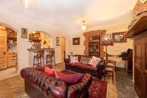Sink into rich leather Chesterfields beneath golden lamplight, surrounded by exposed brick and original stonework that speak to the home`s enduring history.
